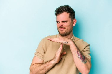 Mavi arka planda izole edilmiş genç beyaz bir adam bir mola hareketi gösteriyor..