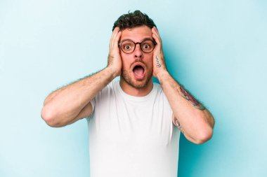 Mavi arka planda izole genç beyaz adam şok oldu, o önemli bir toplantı hatırladı.