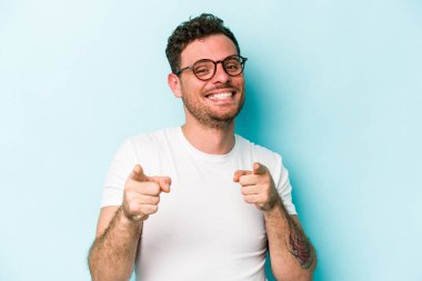 Mavi arka planda izole edilmiş genç beyaz adam öne bakan neşeli gülümsemeler.