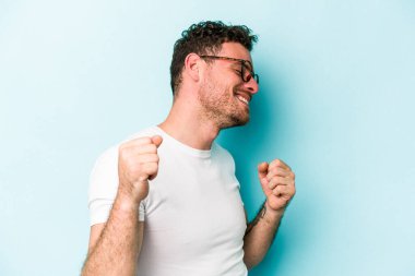 Genç beyaz adam mavi arka planda izole edilmiş dans ediyor ve eğleniyor..