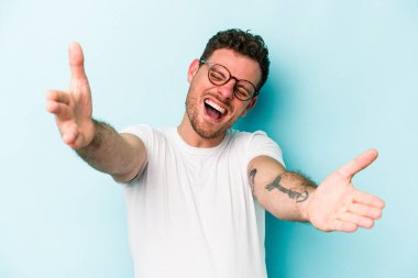 Mavi arka planda izole edilmiş genç beyaz adam kameraya sarıldığı için kendinden emin hissediyor..