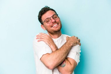 Kafkasyalı genç adam mavi arka planda izole edilmiş, güler yüzlü ve mutlu..