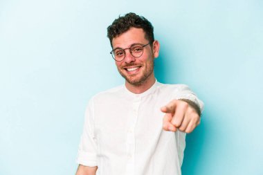 Mavi arka planda izole edilmiş genç beyaz adam öne bakan neşeli gülümsemeler.
