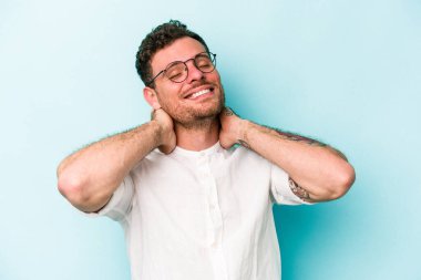 Kafkasyalı genç adam mavi arka planda izole edilmiş. Kendine güveniyor, elleri başının arkasında..