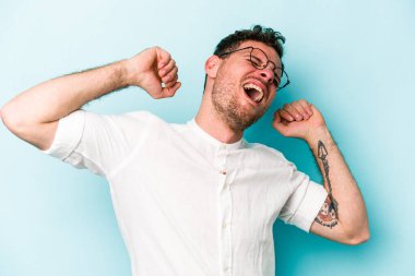 Mavi arka planda izole edilmiş genç beyaz adam kollarını uzatıyor, rahat bir konumda..