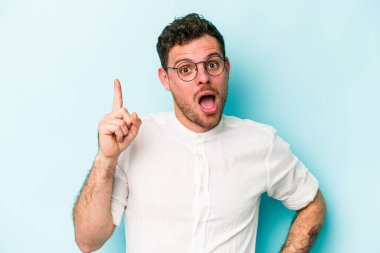 Kafkasyalı genç bir adam mavi arka planda izole edilmiş. Bir fikri, ilham verici bir fikri var..