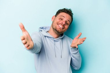 Mavi arka planda izole edilmiş genç beyaz adam kameraya sarıldığı için kendinden emin hissediyor..