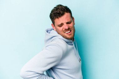 Mavi arka planda izole edilmiş beyaz bir adam sırt ağrısı çekiyor..