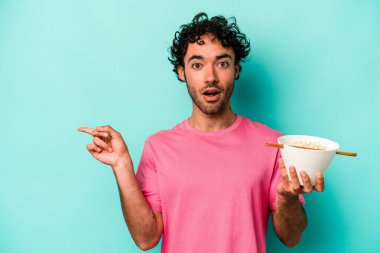 Mavi arka planda izole edilmiş erişte yiyen genç beyaz adam...