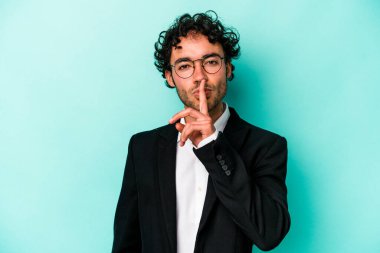 Kafkasyalı genç iş adamı mavi arka planda izole edilmiş bir şekilde ya sır saklıyor ya da sessizlik istiyor..