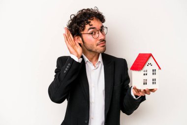 Beyaz arka planda izole edilmiş bir oyuncak evi tutan Kafkasyalı genç bir iş adamı bir dedikoduyu dinlemeye çalışıyor..