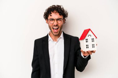 Beyaz arka planda izole edilmiş oyuncak evi tutan Kafkasyalı genç bir iş adamı çok sinirli ve agresif çığlıklar atıyor..