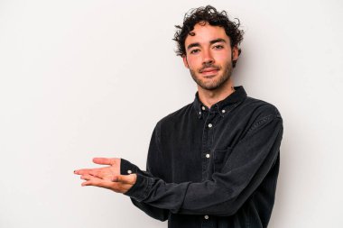 Beyaz arka planda izole edilmiş beyaz tenli genç bir adam palmiyesinde bir kopya alanı tutuyor..