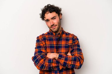 Beyaz arka planda izole edilmiş genç beyaz bir adam şüpheli, belirsiz, seni muayene ediyor..