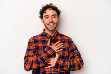 Beyaz arka planda izole genç beyaz adam mutlu bir şekilde gülüyor ve ellerini karnının üstünde tutarak eğleniyor..