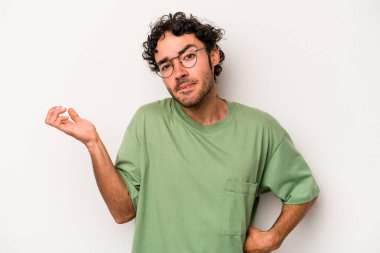 Beyaz arka planda izole edilmiş genç beyaz bir adam sorgulama sırasında omuz silkiyor ve şüphe duyuyor..