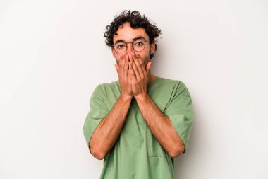 Beyaz arka planda izole edilmiş genç beyaz adam elleriyle ağzını kapatırken şok oldu..