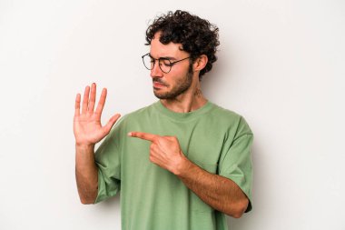 Beyaz arka planda izole edilmiş genç beyaz bir adam gülümseyerek beş numarayı parmaklarıyla gösteriyor..