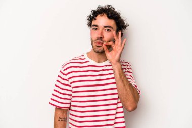 Beyaz arka planda izole edilmiş beyaz tenli genç bir adam parmakları dudaklarında bir sır saklıyor..