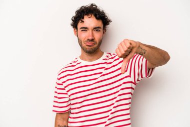 Beyaz arka planda izole edilmiş genç beyaz bir adam baş parmağını aşağı gösteriyor ve hoşlanmadığını ifade ediyor..