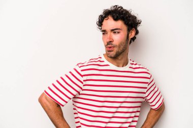 Beyaz arka planda izole edilmiş genç beyaz adam gülümseyen, neşeli ve keyifli bir tarafa bakıyor..