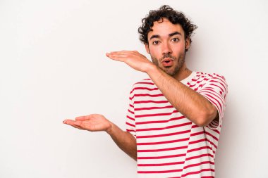 Beyaz arka planda izole edilmiş genç beyaz adam elleri arasında bir kopya alanı tutarken şok ve hayrete düştü..