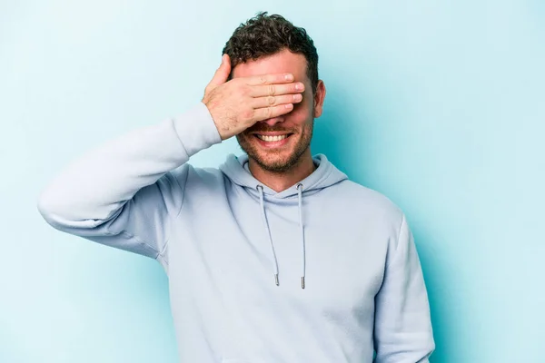 Mladý Běloch Izolovaný Modrém Pozadí Zakrývá Oči Rukama Usmívá Čeká — Stock fotografie