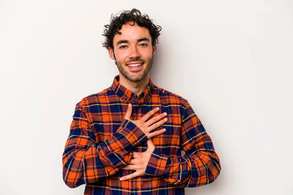 Beyaz arka planda izole genç beyaz adam mutlu bir şekilde gülüyor ve ellerini karnının üstünde tutarak eğleniyor..