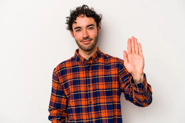 Beyaz arka planda izole edilmiş genç beyaz bir adam gülümseyerek beş numarayı parmaklarıyla gösteriyor..