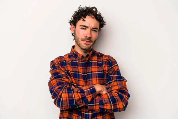 Beyaz arka planda izole edilmiş genç beyaz adam alaycı bir ifadeyle kameraya bakıyor..