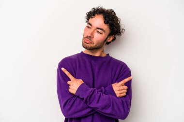 Beyaz arka plan noktalarında izole genç beyaz adam, iki seçenek arasında seçim yapmaya çalışıyor.