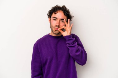 Beyaz arka planda izole edilmiş beyaz tenli genç bir adam parmakları dudaklarında bir sır saklıyor..