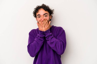 Beyaz arka planda izole edilmiş genç beyaz adam şok olmuş, ağzı ellerle kaplanmış, yeni bir şey keşfetmeye hevesli..