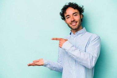 Beyaz arka planda izole edilmiş genç beyaz bir adam, palmiye üzerinde bir fotokopi alanı tutarken heyecanlı..