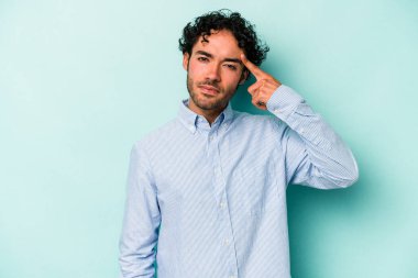 Beyaz arka planda izole edilmiş genç beyaz bir adam şakağı parmağıyla işaret ediyor, düşünüyor ve bir göreve odaklanıyor..