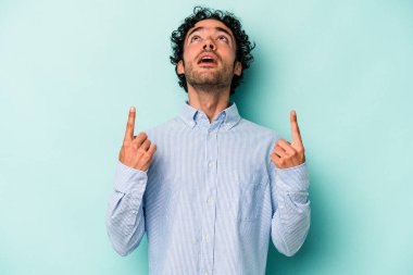 Beyaz arka planda izole edilmiş genç beyaz adam ağzı açık bir şekilde üst tarafı işaret ediyor..