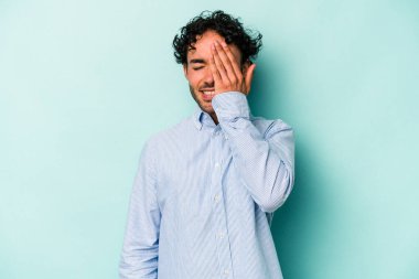 Beyaz arka planda izole edilmiş genç beyaz bir adam yüzünün yarısını palmiye ile örterek eğleniyor..