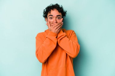 Beyaz arka planda izole edilmiş genç beyaz adam elleriyle ağzını kapatırken şok oldu..