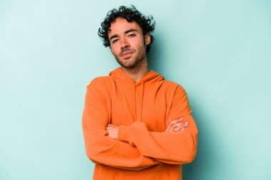 Beyaz arka planda izole edilmiş genç beyaz adam alaycı bir ifadeyle kameraya bakıyor..