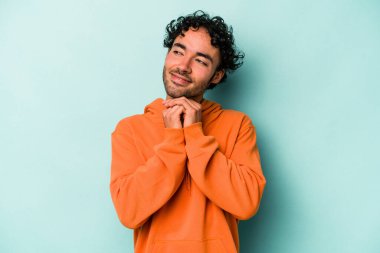 Beyaz arka planda izole genç beyaz adam ellerini çenesinin altında tutuyor, mutlu bir şekilde yana bakıyor..