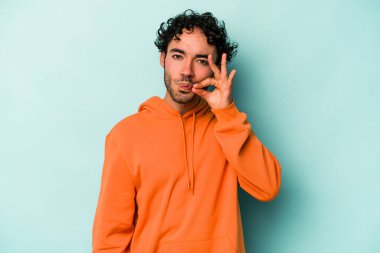 Beyaz arka planda izole edilmiş beyaz tenli genç bir adam parmakları dudaklarında bir sır saklıyor..