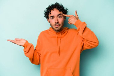 Beyaz arka planda izole edilmiş genç beyaz bir adam elinde bir ürün tutuyor ve.