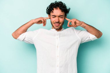 Beyaz arka planda izole edilmiş genç beyaz bir adam parmaklarıyla kulaklarını kapatıyor, gürültülü bir ortam yüzünden stresli ve çaresiz..