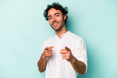 Beyaz arka planda izole edilmiş genç beyaz adam parmaklarıyla ön tarafı işaret ediyor..