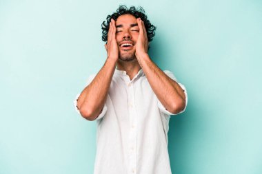 Beyaz arka planda izole olmuş genç beyaz bir adam ellerini başının üstünde tutarak neşeyle gülüyor. Mutluluk kavramı.