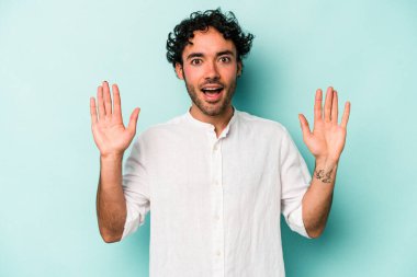 Beyaz arka planda izole genç beyaz adam hoş bir sürpriz alıyor, heyecanlı ve el kaldırıyor..