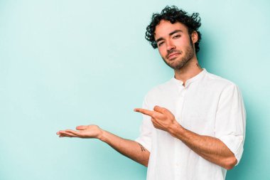 Beyaz arka planda izole edilmiş genç beyaz bir adam, palmiye üzerinde bir fotokopi alanı tutarken heyecanlı..