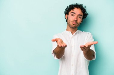 Beyaz arka planda izole edilmiş genç beyaz bir adam dudaklarını katlıyor ve hava öpücüğü vermek için avuç içleri tutuyor..