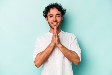 Beyaz arka planda izole edilmiş genç beyaz bir adam el ele tutuşup, ağız kenarında dua ediyor, kendinden emin..
