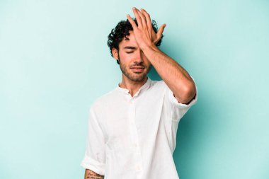 Beyaz arka planda izole edilmiş genç beyaz bir adam bir şeyi unutuyor. Alnına avuç içi ve gözlerini kapayarak vuruyor..